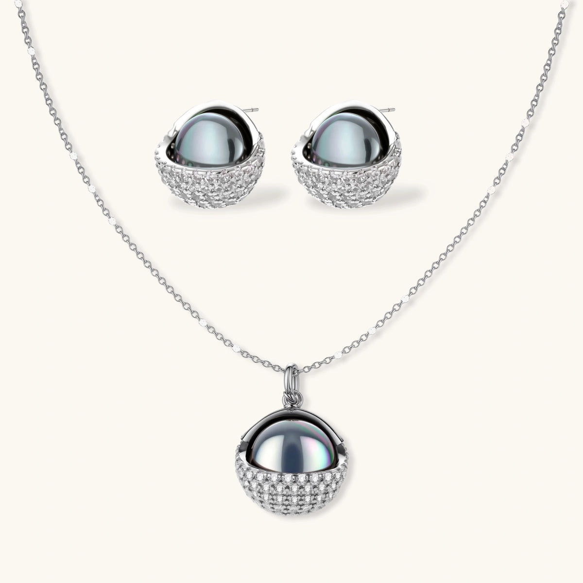 Silver gray Tahitian-style pearl pendant necklace and matching pave zirconia stud earrings set on cream background.
