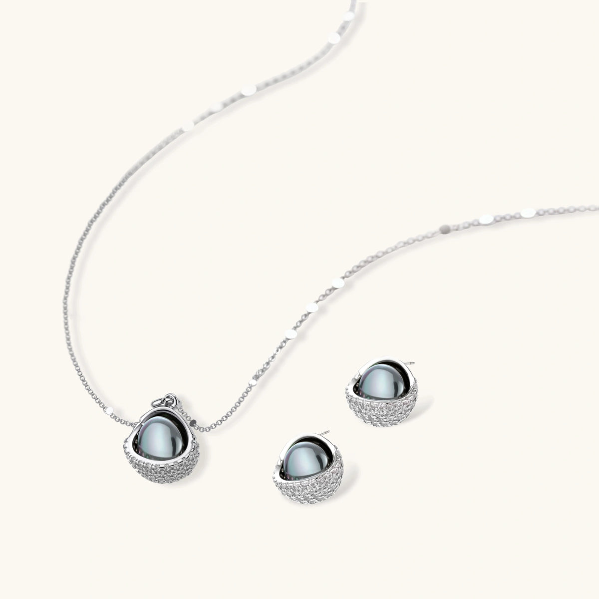 Silver gray Tahitian-style pearl pendant necklace and matching pave zirconia stud earrings set on cream background.